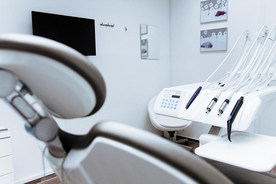 A dentist chair with dentistry tools next to it.